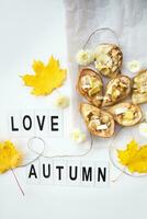 gebacken Birnen mit Brie Käse und Nüsse auf ein Hintergrund von Herbst Gelb Blätter, das Inschrift Liebe Herbst foto