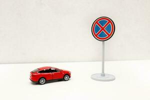 Spielzeug rot Auto im Vorderseite von ein Straße Zeichen Nein anhalten mit Kopieren Raum foto