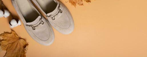 Wildleder- Schuhe mit Herbst Blätter und Baumwolle Süßigkeiten auf Orange Hintergrund oben Sicht. beiläufig Mode eben legen mit Kopieren Raum. foto