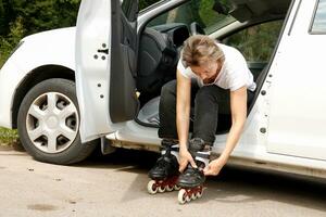 Frau Ändern Schuhe in Rollerblades im ein Auto im das Park foto