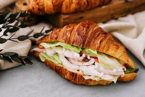 Croissant Sandwich mit Schinken, Tomate und Grüner Salat foto