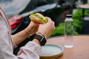 Frau Essen Burger Sandwich beim draussen Terrasse Bistro foto