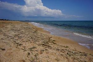 goldener Strand mit Algen am strahlend blauen Meer foto