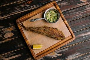 gebraten Fisch auf hölzern Tafel mit würzig Soße foto