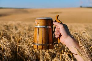 Hand halten ein hölzern Becher mit Bier foto