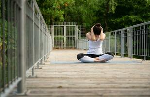 jung weiblich auf ein hölzern Brücke im das Park mit gesund Yoga Aktivitäten foto