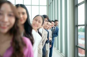 Gruppe von Geschäft Menschen Stehen im Linie im Konferenz Zimmer benutzt zum Treffen im modern Büro, Fokus auf das zuletzt Person foto