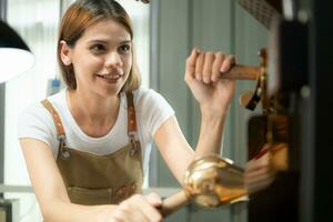 Porträt von ein jung Frau Arbeiten mit ein Kaffee Bräter Maschine foto