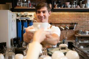 Porträt von ein lächelnd männlich Barista halten ein Tasse von Kaffee foto