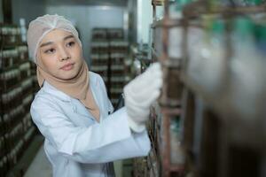 jung asiatisch Muslim weiblich Wissenschaftler tun Forschung beim ein Pilz Fabrik, Prüfung Pilz Sauerteig Agent im ein steril und temperaturgesteuert Zimmer. foto