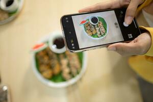 Frau nehmen Foto von Pilz Essen mit Smartphone beim Tabelle im gesund Restaurant