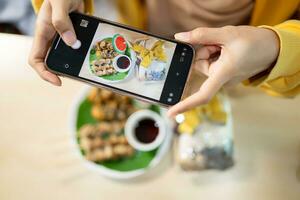 Frau nehmen Foto von Pilz Essen mit Smartphone beim Tabelle im gesund Restaurant