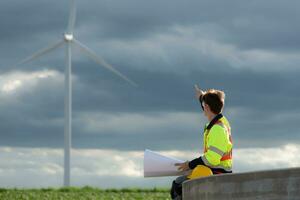 jung Ingenieur Arbeiten auf ein Wind Turbine Feld suchen beim das Entwurf im das Mitte von das schwarz Wolken mit Sonnenlicht leuchtenden, das Konzept von natürlich Energie von Wind. foto