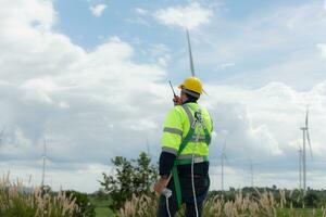 Ingenieure sind mit ein Smartphone zu prüfen das Wind Turbine im das Feld, das Konzept von natürlich Energie von Wind. foto