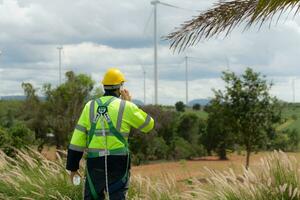 Ingenieure sind mit ein Smartphone zu prüfen das Wind Turbine im das Feld, das Konzept von natürlich Energie von Wind. foto