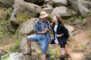 jung Paar Wandern im das Wald mit Rucksäcke und Trekking Stangen foto