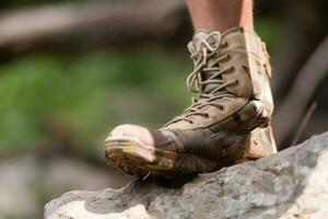 Wandern Schuhe auf ein Log oder Felsen im das Wald. foto