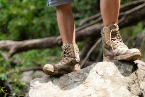 Wandern Schuhe auf ein Log oder Felsen im das Wald. foto