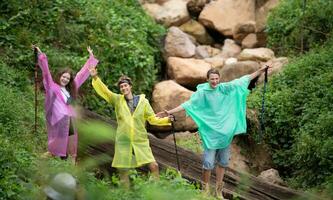 Gruppe von glücklich freunde im Regenmäntel haben Spaß im das Wald foto