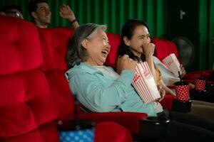 Gruppe von asiatisch Senior freunde Aufpassen Komödie Film und Lachen beim das Kino mit Popcorn foto