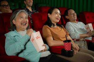 Gruppe von asiatisch Senior freunde Aufpassen Komödie Film und Lachen beim das Kino mit Popcorn foto