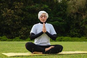 attraktive Frau im Hijab-Training im Park, meditierend. foto