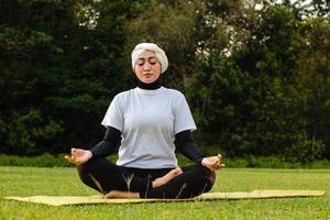 attraktive Frau im Hijab-Training im Park, meditierend. foto