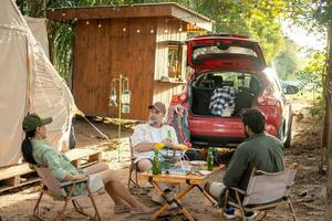 Gruppentouristen trinken Bieralkohol und spielen Gitarre zusammen mit Spaß und Glück im Sommer beim Camping foto