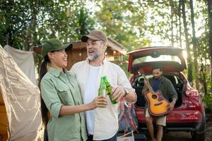 Gruppentouristen trinken Bieralkohol und spielen Gitarre zusammen mit Spaß und Glück im Sommer beim Camping foto