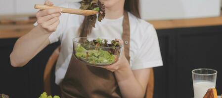 köstlich Obst und Gemüse auf ein Tabelle und Frau Kochen. Hausfrau ist Schneiden Grün Gurken auf ein hölzern Tafel zum Herstellung frisch Salat im das Küche. foto