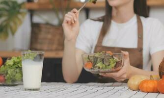 köstlich Obst und Gemüse auf ein Tabelle und Frau Kochen. Hausfrau ist Schneiden Grün Gurken auf ein hölzern Tafel zum Herstellung frisch Salat im das Küche. foto