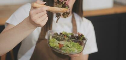 köstlich Obst und Gemüse auf ein Tabelle und Frau Kochen. Hausfrau ist Schneiden Grün Gurken auf ein hölzern Tafel zum Herstellung frisch Salat im das Küche. foto