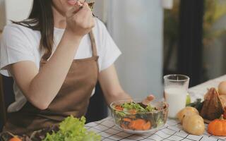 köstlich Obst und Gemüse auf ein Tabelle und Frau Kochen. Hausfrau ist Schneiden Grün Gurken auf ein hölzern Tafel zum Herstellung frisch Salat im das Küche. foto