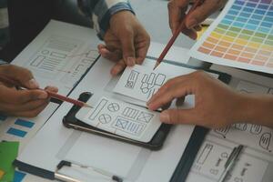 Nahaufnahme von UX-Entwicklern und UI-Designern beim Brainstorming über das Wireframe-Design der mobilen App-Schnittstelle auf dem Tisch mit Kundeninformationen und Farbcode in der Agentur für moderne digitale Entwicklung von Office.Creative foto