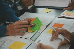 Nahaufnahme von UX-Entwicklern und UI-Designern beim Brainstorming über das Wireframe-Design der mobilen App-Schnittstelle auf dem Tisch mit Kundeninformationen und Farbcode in der Agentur für moderne digitale Entwicklung von Office.Creative foto