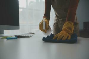 Büro Reinigung Service. Hausmeister Sprühen Schreibtisch. Arbeitsplatz Hygiene foto