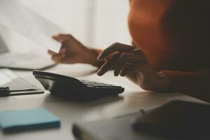 asiatische geschäftsfrau, die laptop-computer verwendet und im büro mit taschenrechnerdokument auf schreibtisch arbeitet, plant die analyse des finanzberichts, geschäftsplaninvestitionen, finanzanalysekonzept. foto