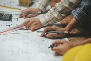 Mannschaft von multiethnisch Architekten Arbeiten auf Konstruktion Pläne im Treffen Zimmer. Ingenieure diskutieren auf Projekt im Büro. reifen Geschäftsmann und Frau Stehen um Tabelle Arbeiten auf Entwurf. foto