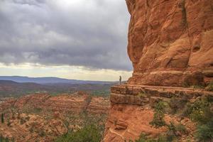 Frau steht auf einer Klippe neben roten Felsen foto