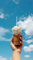 Hand halten vereist Kaffee im ein Plastik Tasse mit ein Blau Himmel und Wolke Hintergrund. ai generiert foto