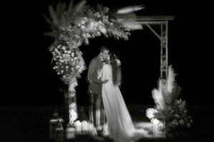 Braut und Bräutigam gegen das Hintergrund von ein Abend Hochzeit Bogen foto