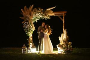 Braut und Bräutigam gegen das Hintergrund von ein Abend Hochzeit Bogen foto