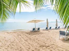 Outdoor mit Sonnenschirm und Stuhl am wunderschönen tropischen Strand und Meer foto