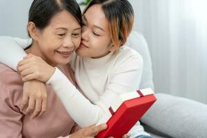 Mutter Tag, süß asiatisch Teen Mädchen geben Geschenk Box zu reifen Mitte Alter Mama. Liebe, Kuss, Pflege, glücklich Lächeln genießen Familie Zeit. feiern Besondere Gelegenheit, glücklich Geburtstag, glücklich Neu Jahre, fröhlich Weihnachten foto