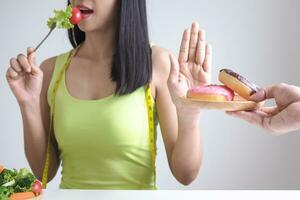 schlank Körper Frauen wählen während gesund Lebensmittel und Krapfen, weiblich wählen Salat zum Diät. gut gesund Lebensmittel. Gewicht verlieren, Gleichgewicht, Kontrolle, reduzieren fett, niedrig Kalorien, Routinen, Übung. foto