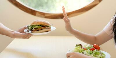 schönheit schlank weiblicher körper verwirren hamburger. frau im restaurant erreicht gewichtsverlustziel für ein gesundes leben, verrückt nach dünnheit, dünner taille, ernährungsberaterin. Ernährung, Körperform. foto