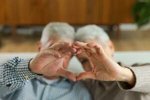 Liebe Herz gestalten Frieden. Senior älter Paar Herstellung Herz gestalten mit ihr Hände. Erwachsene reifen alt Mann Ehefrau zeigen Herz unterzeichnen. glücklich Rentner Familie. ich Liebe Sie glücklich Valentinsgrüße Tag. foto