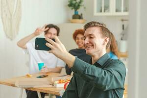 Prost funky Stimmung. glücklich Gruppe von freunde machen Selfie. Mann nehmen Foto von freunde beim Party. Gruppe von gemischtrassig jung Menschen nehmen Foto auf Telefon. jung Menschen genießen ihr Unternehmen Lächeln haben Spaß.