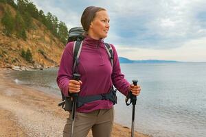 Wandern Tourismus Abenteuer. Backpacker Wanderer Frau suchen beim schön Sicht. Wanderer Mädchen Dame Tourist mit Rucksack Gehen in der Nähe von See. jung glücklich Frau genießen Wanderung Trekking Tourismus aktiv Urlaub. foto