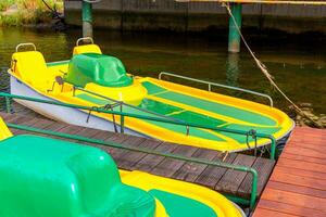 Tretboote oder Tretboote Katamarane Station. Gelbe Wasserfahrräder, die an sonnigen Sommertagen am Pier des Yachthafens am See gesperrt sind. Sommerfreizeitbeschäftigung im Freien. foto